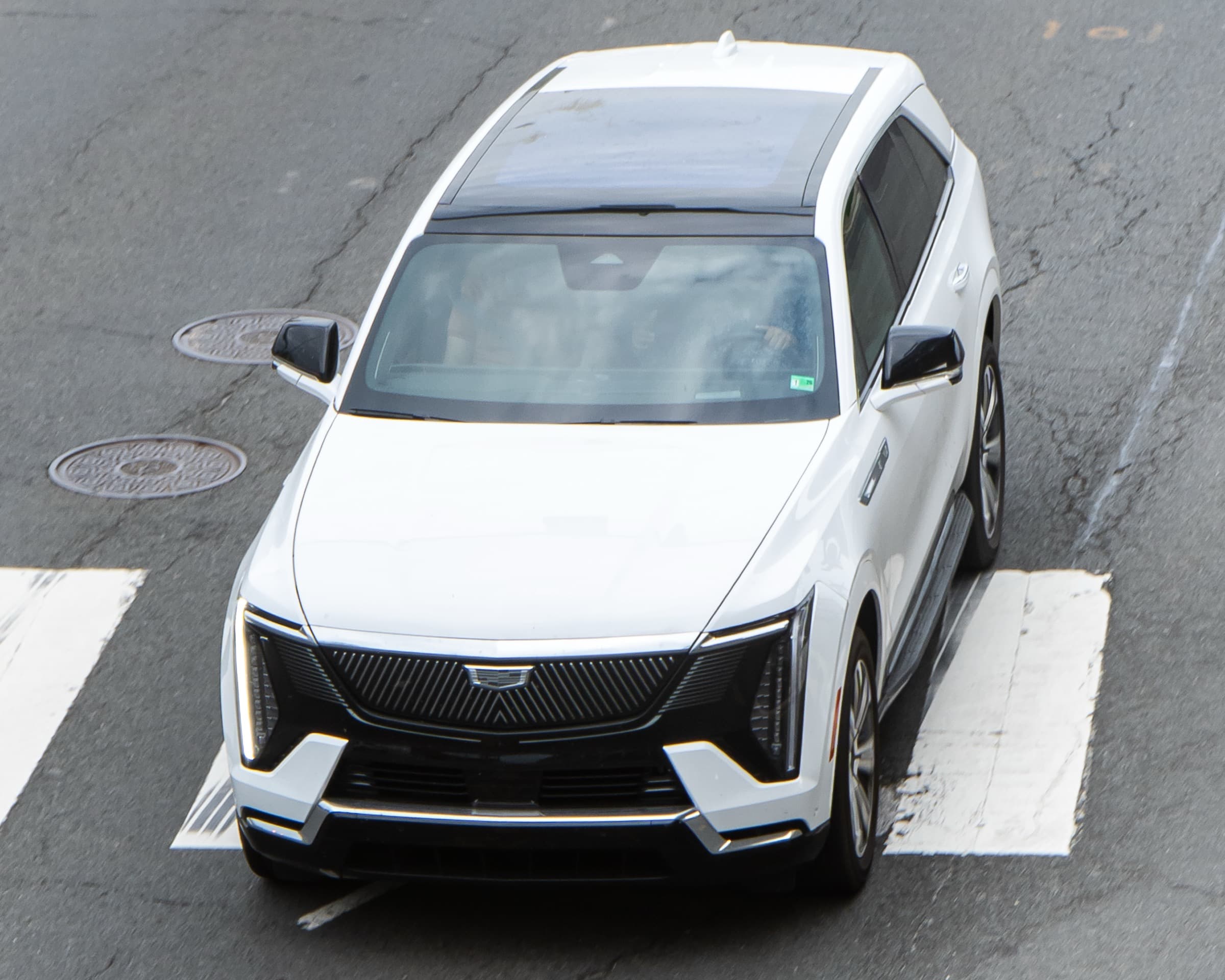 Cadillac Escalade IQ in white driving on a city street, viewed from above