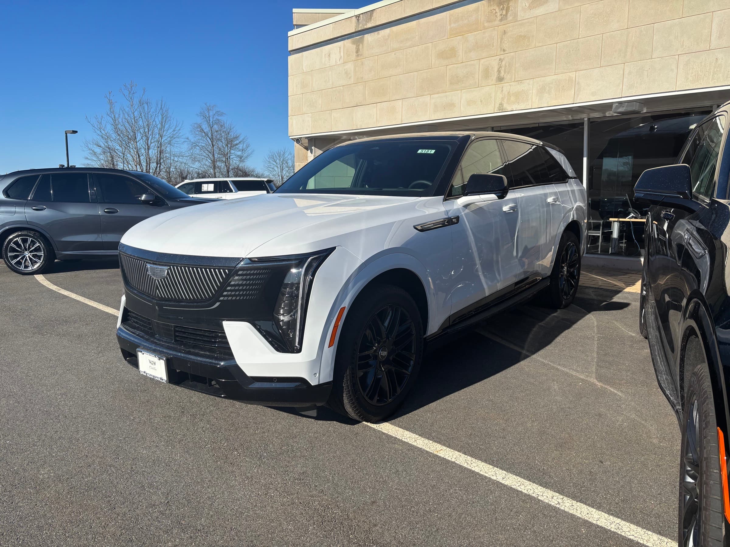 2026 Cadillac Escalade IQ in white, front three-quarter view at a Cadillac dealership