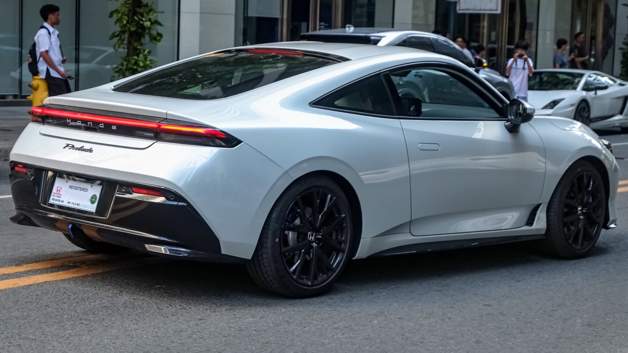 2026 Honda Prelude rear three-quarter view in white, showing the full-width taillights and liftback roofline