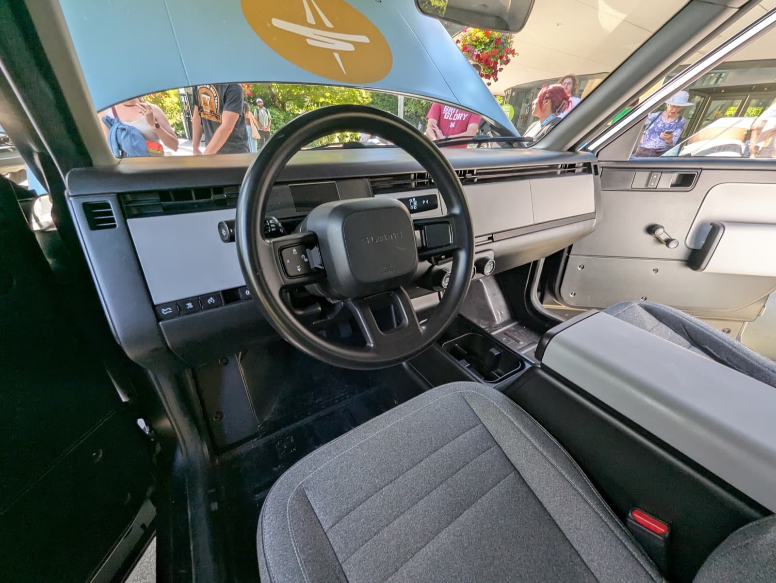 Driver's-side interior of a Slate Truck demonstration vehicle showing the minimalist dashboard and manual window crank