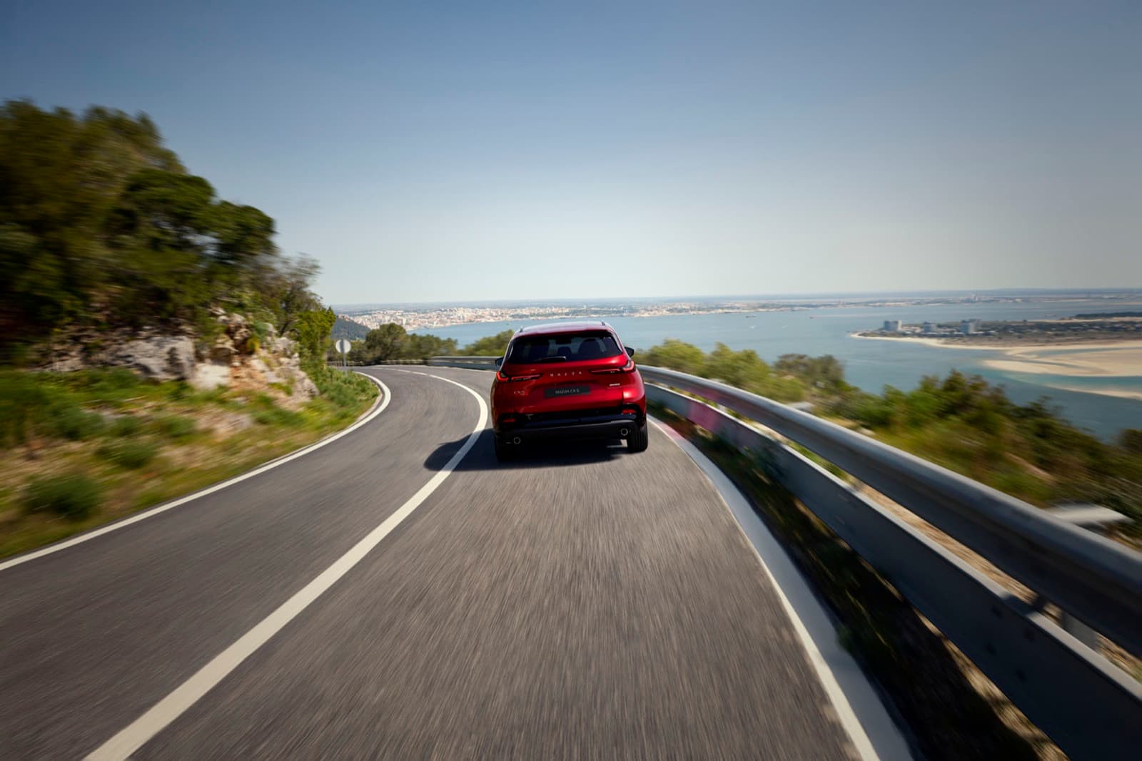 2026 Mazda CX-5 in Soul Red Crystal driving on a coastal road, official Mazda press image