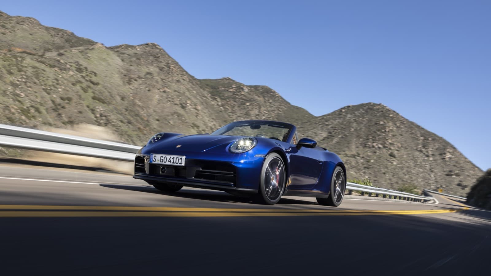 2026 Porsche 911 Carrera S Cabriolet in Gentian Blue driving on a mountain road