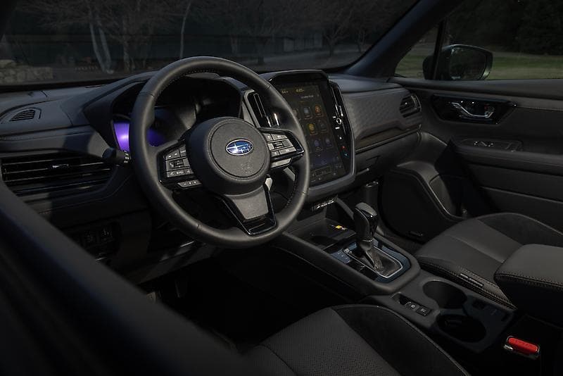 Subaru Forester front cockpit with steering wheel, digital gauge cluster, and center touchscreen