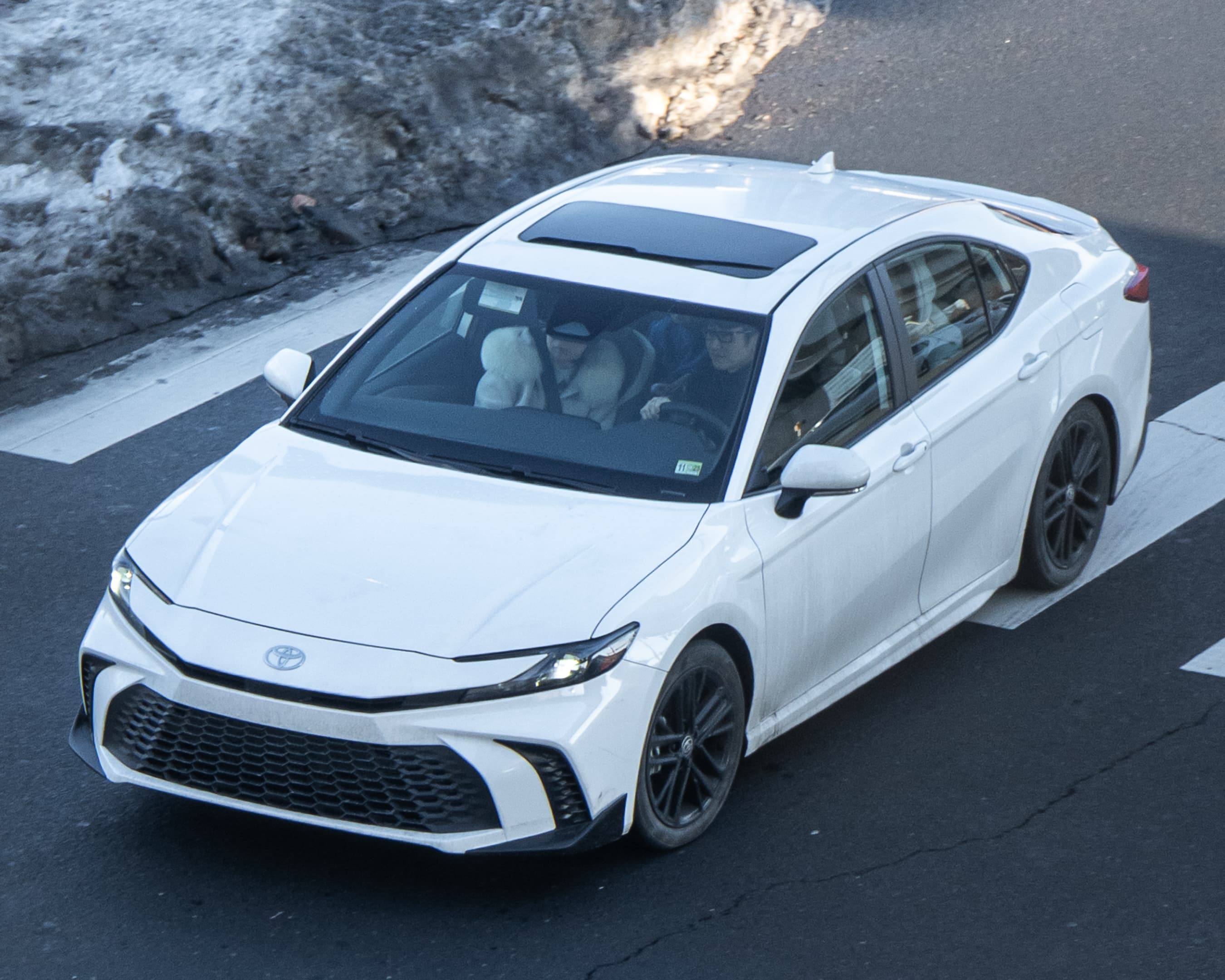 Ninth-generation Toyota Camry driving on a public road, front three-quarter view from above